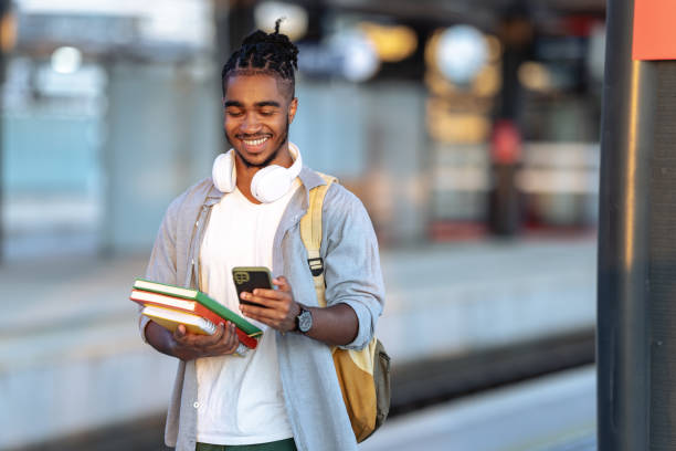 istock Latin male student waiting for a train and checking smart phone 2150745157