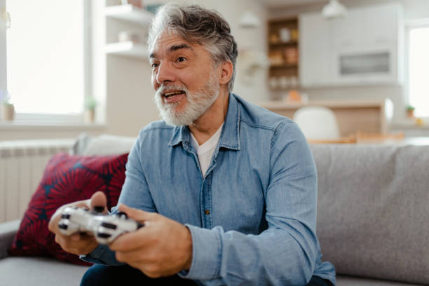 istock Man Sitting on Sofa Playing Video Game in Living Room 2150746675