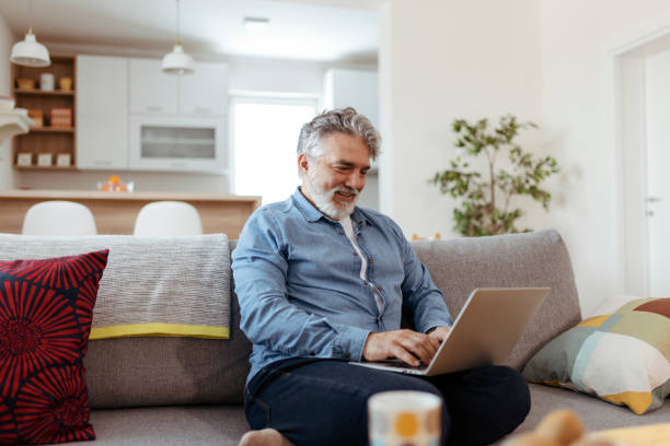 istock Man Working On Laptop Sitting On Sofa At Home 2150746764