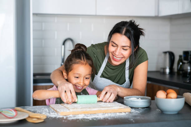 istock Mother teaching her daughter how to roll the dough while baking 2150750456