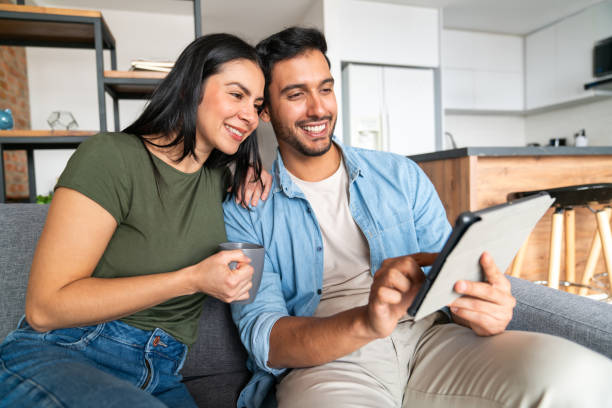 Happy couple at home making a reservation using a digital tablet