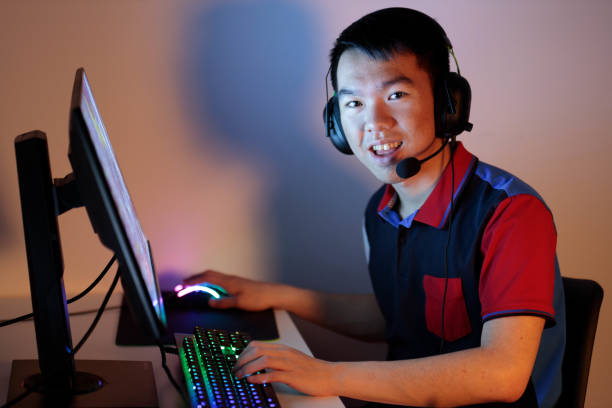 istock Teenager with headphones playing video game on computer looking at camera 2150751618