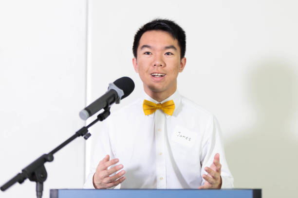 istock A young man at a podium, speaking into a microphone at a presentation 2150751653