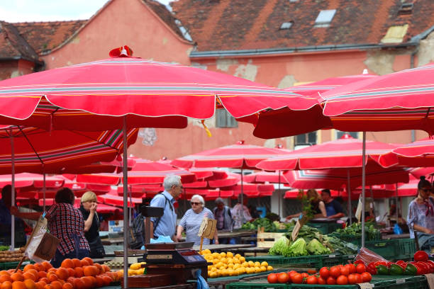Zagreb, Croatia - May 13, 2022: Traditional red umbrellas on Dolac market in Zagreb, Croatia. Locals and tourists are shopping for fresh produce and flowers.