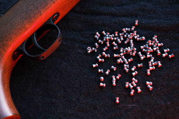 Rifle gun trigger with air pellets for hunting on cloth dark background with red light.