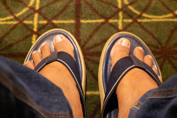 A man feet wearing a blue slippers on a carpet floor at cinema, Top view of feet in blue slippers.