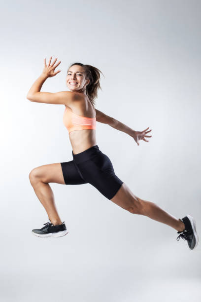 istock Energetic young woman in sportswear jumping with joy in studio setting 2150760979