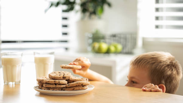 istock A boy is peeping at an appetizing stack of freshly baked chocolate cookies on the table. 2150763718