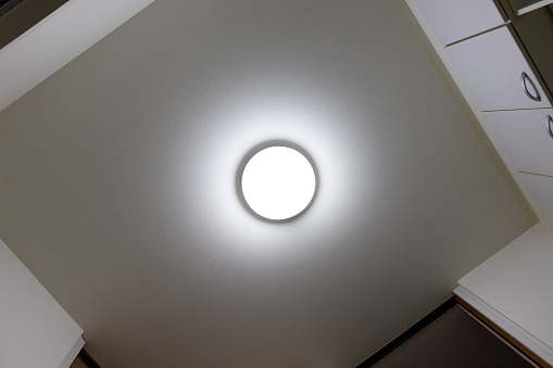 View from directly below of a ceiling light illuminating a dimly lit room