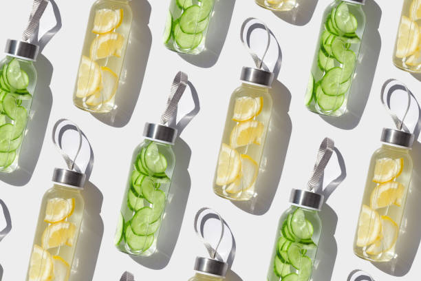 istock Cleansing, refreshing Lemon, cucumber water drink detox, shadow at sunlight on white. Wellness, alkaline diet, eating healthy concept. Stylish glass reusable water bottle, top view pattern 2150766556