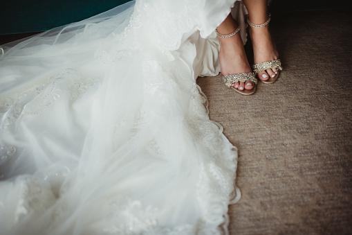 Bride putting on dress and shoes for her wedding