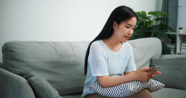 istock Young woman uses mobile phone on sofa at home. 2150769322