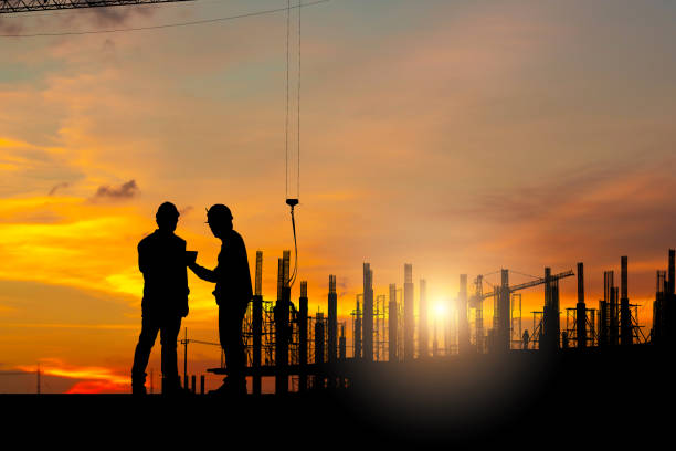 istock Silhouette of Engineer and worker team checking project at building site background, a construction site with sunset 2150771705
