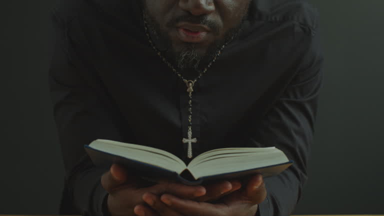 Clergyman Holding Opened Bible and Reading Prayer Aloud