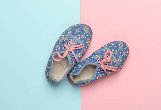 Children's used sneakers on pink blue background