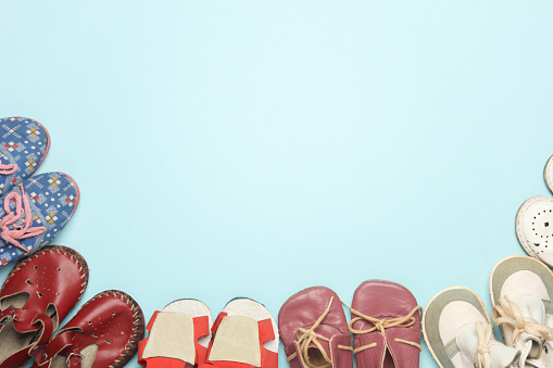 Many different children's shoes on a blue background. Copy space
