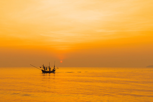 Fishermen on their boats are returning to shore in the morning as the sun rises.