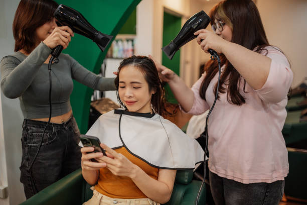 istock Smiling woman using her phone at a hair salon 2150778001