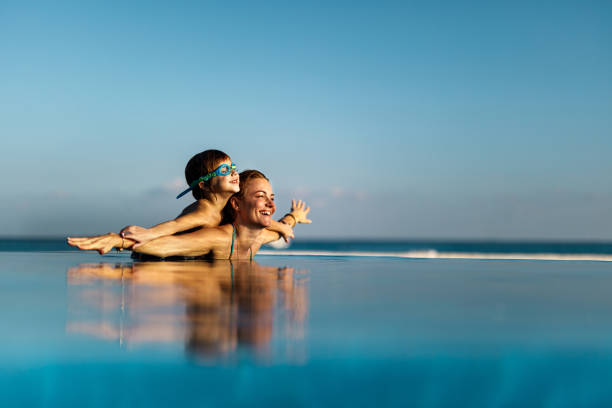 Carefree boy having fun with his single mother in infinity pool.