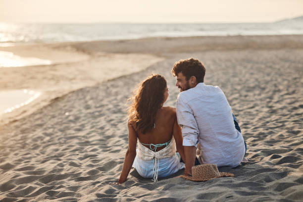 istock Back view of happy couple talking on the beach. 2150782059