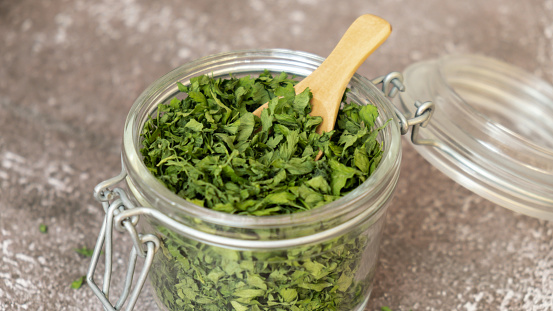 Glass jar with green dry parsley. Vegetarian bio organic salad herb healthy eating. Home garden immunity-boosting herbs. Seasonal harvest cottagecore