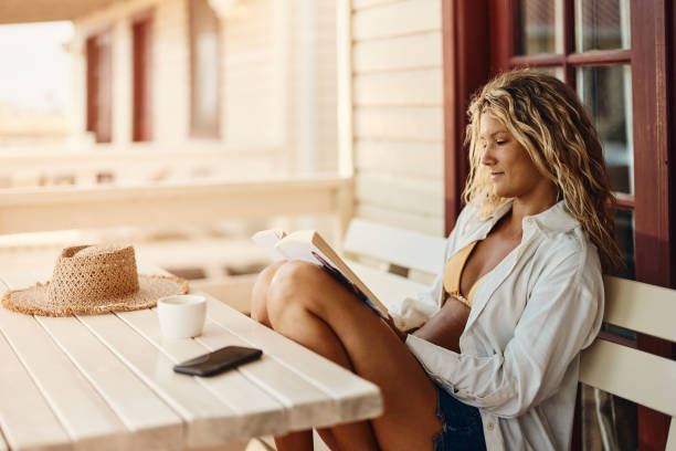 istock Smiling woman reading a book on a patio. 2150782318
