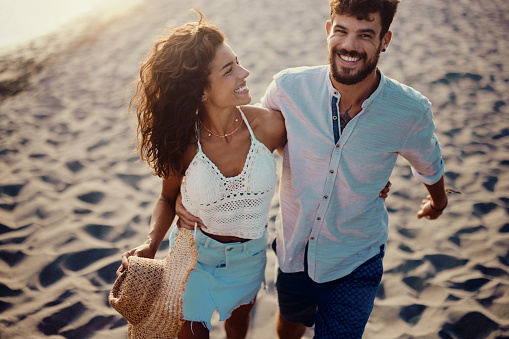 Young happy couple taking a walk on the beach. Copy space.
