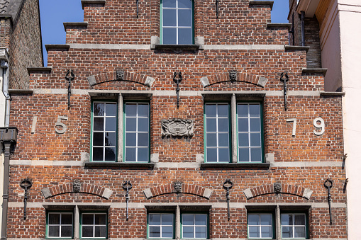 Bruges, Belgium - May 19, 2023:  Decorative facade of historic tenement house built of red brick, located in Old Town