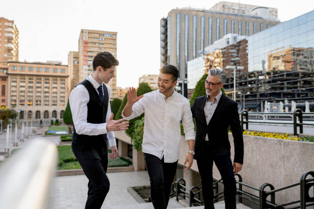 a group of three black men in stylish suits a meeting in a summer park. African-Americans friends hispanic businessman greeting pose outdoors