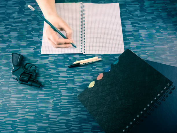 istock Mature woman holding a pencil above math notebook and firearm on table 2150784648