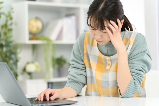 istock A woman wearing an apron holding her head while working on a computer 2150785900