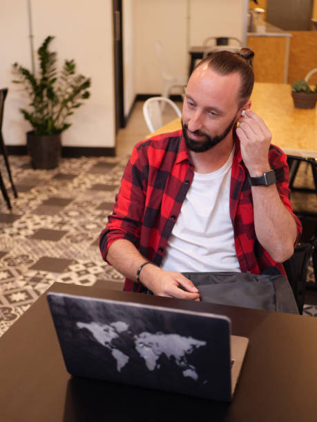 istock Man using earbuds and working in a coffee shop 2150786951