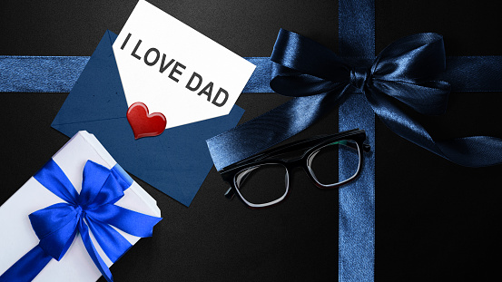 Black ribbon with eyeglasses and a gift box with a letter with I Love Dad text. Fathers day concept