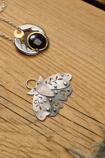 Jeweler craft workshop  Jeweler,  produces hand made  a Locket, butterfly  pendant, on old wooden table.   Vintage and modern jeweler tools  Work Hand Tool  DIY. Small business