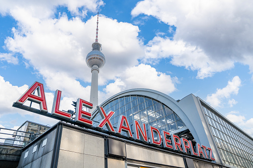Alexanderplatz Station and Berlin TV Tower on the blue sky background with fluffy clouds.