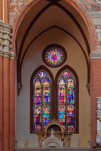 Bologna - Italy. February 11, 2023: A vertical capture inside San Petronio Basilica, Bologna, showcasing the vibrant colors of the stained glass windows set in Gothic arches