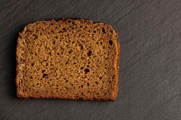 sliced black bread on a black slate board, square-shaped pieces of fresh bread
