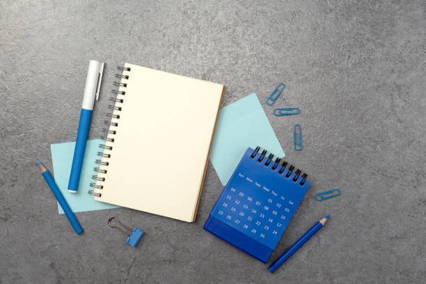 istock Notebook and blue stationery on stone texture background. Work desk space 2150796028