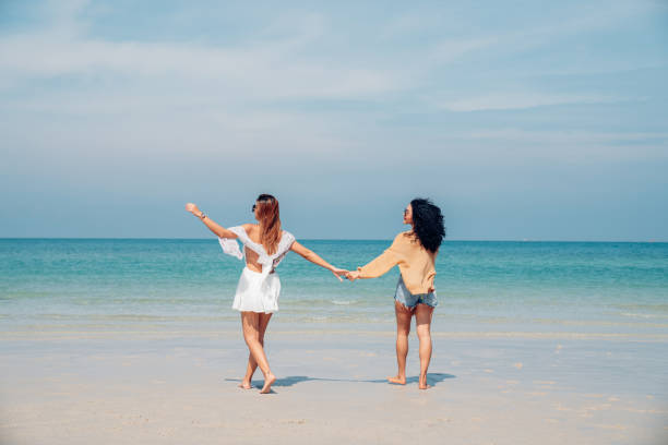 istock Two woman walking and dancing together on the beach. 2150798791