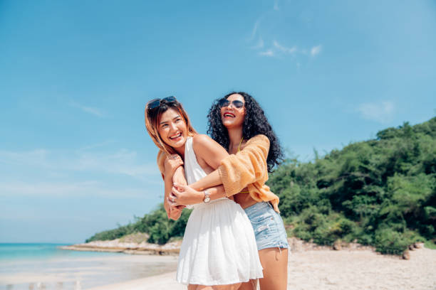 istock Two woman walking and dancing together on the beach. 2150799660