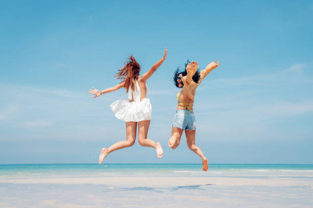 istock Two woman walking and dancing together on the beach. 2150799663