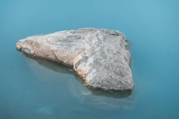 A large rock or boulder near the shore of Lake Pukaki in the Southern Alps of the South Island.  The turquoise colour is caused glacial sediment suspended in the water. This image was achieved with a 20 second exposure and taken on a cold and sunny evening after sunset on 28 April 2024.