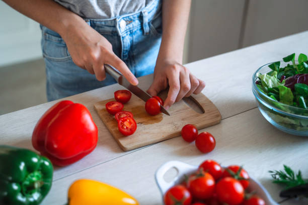 istock Beautiful Girl Preparing Fresh Salad in a Bright Kitchen. 2150801013