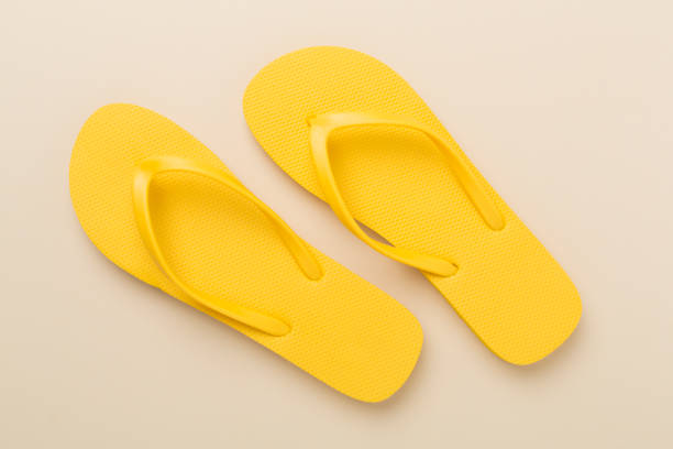 istock Bright yellow flip-flops on color background, top view. Summer concept 2150801751