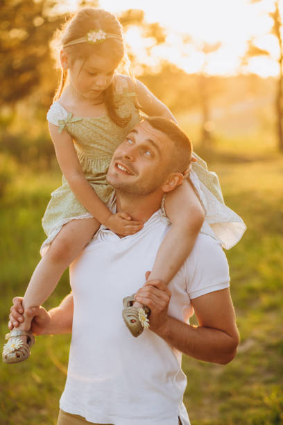 Happy father playing and carrying his daughter on shoulders.