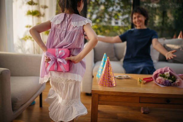Little girl is hiding a present behind her back and walking toward grandma.