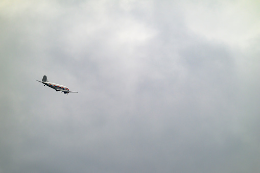 Vintage Douglas DC-3 propellor airplane flying in mid air in a cloudy sky over Zwolle in Overijssel, Netherlands.