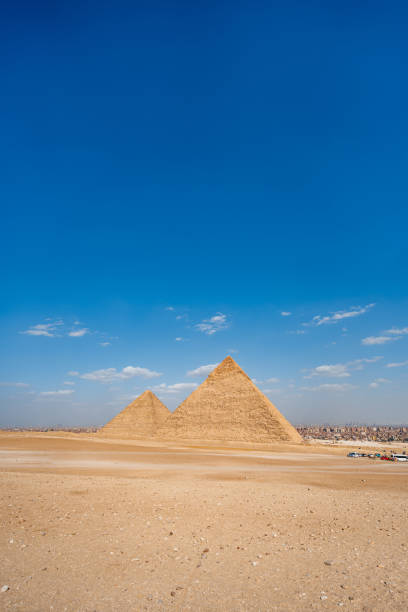 Giza Plateau, Egypt - February 23, 2021  - Wide black and white image of the iconic Sphinx with the Pyramids of Giza in the background on a rare rainy day and a cloudy sky.