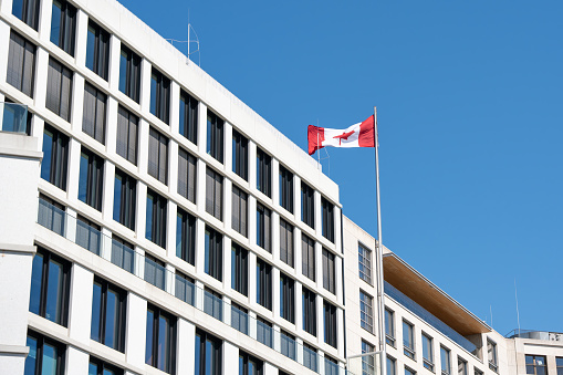 Waving Canadian flag against a blue sky. Canadian flag on the roof of the building.