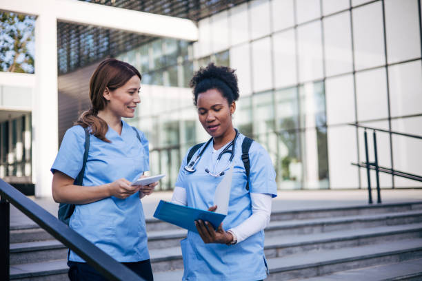 istock Female doctors talking in front of the hospital, going over paperwork 2150804657